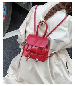 Close-up of red patent leather mini backpack featuring drawstring and brand embossing