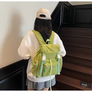 Détail du sac à dos vert en nylon froissé avec fermeture à boucle blanche pratique