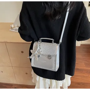 Detail of silver sequined handbag with star charm and leather texture shown on model