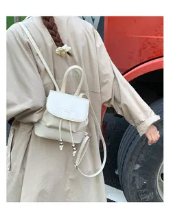 Detail of cream mini backpack featuring drawstring closure and silver metallic bead accents