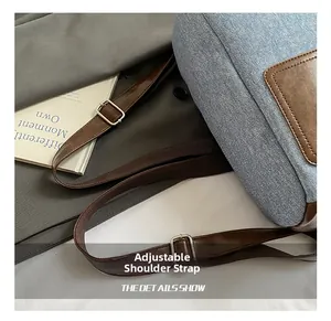 Detail of adjustable brown leather strap with silver metal buckle on blue denim backpack