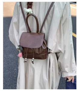 Close-up of a vintage brown leather backpack with drawstring closure and handle detail