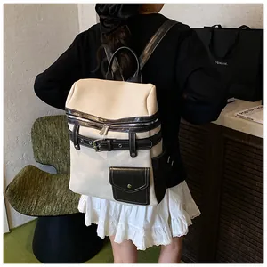 Detail view of large beige canvas backpack with black leather trim and strap buckles