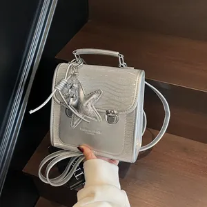 Silver glitter backpack with metallic balloon dog charm on a wooden stair background