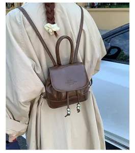 Detail view of vintage brown glossy leather backpack with drawstring and silver bead accents
