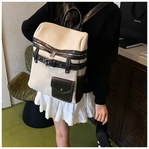 Detail of a beige canvas backpack with black leather trim and silver metal hardware accents