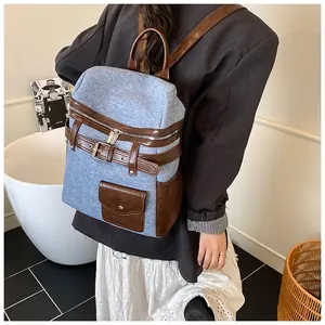 Detailed view of blue textured backpack featuring brown leather straps and metal hardware