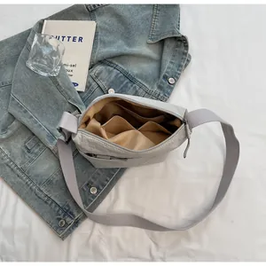 Detail view of the spacious inner pockets and light brown lining of this light grey crossbody bag