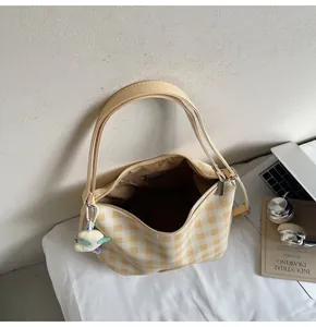 Détail du sac en toile à damier jaune avec pendentif nuage sur un fond blanc