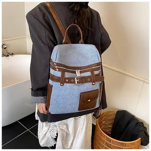 Detail shot of a large denim and leather backpack worn by a model in a casual setting