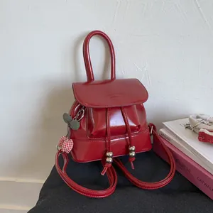 Detail of red glossy mini backpack featuring polished PU leather and cherry charms