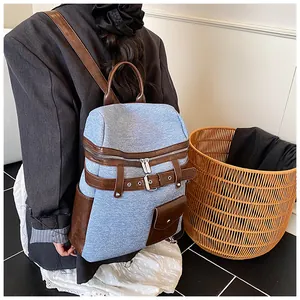Rear view of a light blue denim texture backpack with brown synthetic leather details