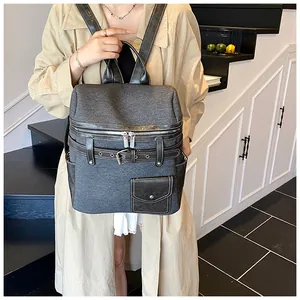 Detailed view of gray fabric backpack with black leather accents and buckle on model
