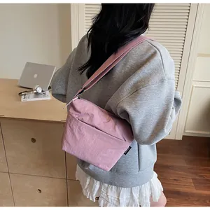 Detail of pink nylon crossbody bag with textured fabric and branded side label
