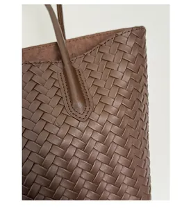Close-up of deep brown woven leather texture with precise stitching on high-end tote bag