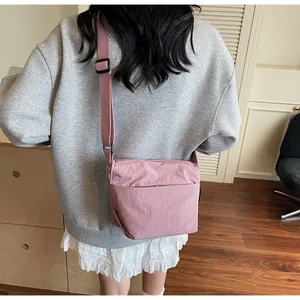 Close-up of pink nylon crossbody bag showing the front pocket and adjustable strap detail