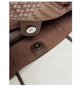 Close-up of brown woven leather texture with silver magnetic closure and soft suede lining