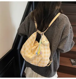 Détail d'un sac à carreaux jaune et blanc avec pendentif lune et glands colorés