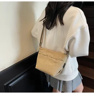 Detailed close-up of a light beige nylon crossbody bag with textured fabric and adjustable strap