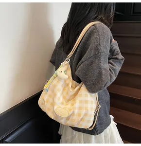 Détail d'un sac cabas à carreaux jaune et blanc avec pendentifs décoratifs et étiquette