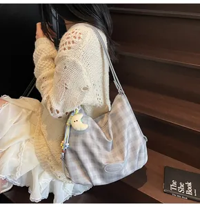 Détail du sac bandoulière à carreaux gris avec charm lune en peluche sur l'escalier