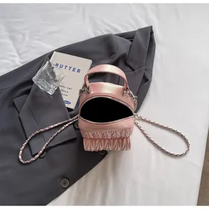 Gros plan du mini sac matelassé rose avec clous en cristal et détails de la bandoulière