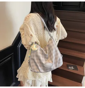 Détail du sac à carreaux gris avec breloque lune jaune sur des escaliers en bois