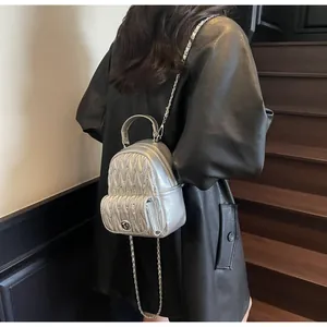 Gros plan d'un mini sac à dos argenté matelassé avec des bandoulières en chaîne chic