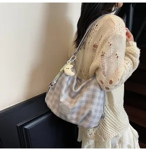 Détail d'un sac à bandoulière à carreaux gris avec un pendentif lune en peluche