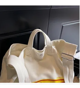 Detail of canvas tote bag showing top handles, adjustable strap and magnetic closure