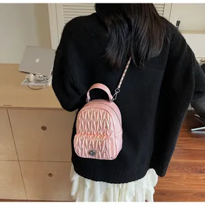 Mini sac à dos matelassé rose avec chaîne en argent porté à l'épaule par le modèle