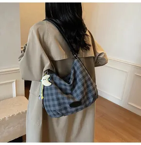 Détail d'un sac cabas à carreaux avec breloque lune en peluche et pompon étoile latéral