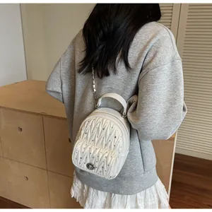 Vue arrière du mannequin portant un mini sac à dos blanc matelassé avec chaîne et fermoir argent