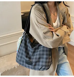 Détail du sac bandoulière à carreaux avec sangle en cuir et breloque peluche mignonne