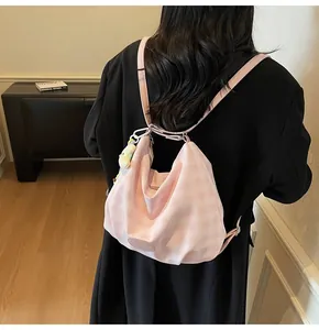 Détail du sac bandoulière en toile à carreaux roses avec breloque peluche et écusson cuir