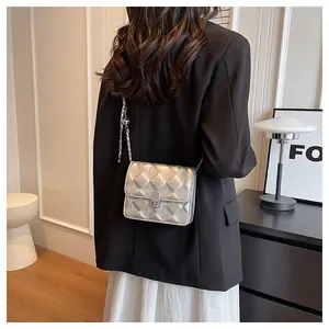 Close-up of silver quilted crossbody bag with metal chain strap on a black blazer