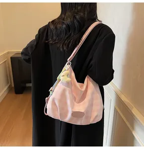 Détail d'un sac à bandoulière en toile à carreaux roses avec pendentif lune sur modèle