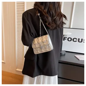 Detail of silver quilted chain bag with diamond texture and metallic lock on model