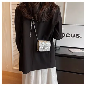 Rear view of silver quilted crossbody bag with metal chain strap on model in modern setting