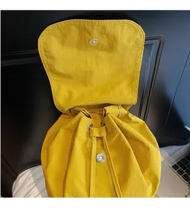 Close-up of drawstring closure and silver magnetic buckle on yellow nylon backpack