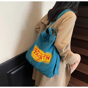 Close-up of blue canvas tote bag with retro graphic print and sturdy shoulder strap
