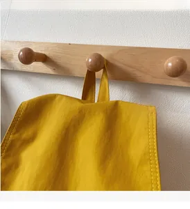Detail of the reinforced top handle on a bright yellow drawstring nylon backpack