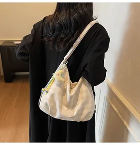 Détail du sac hobo à carreaux avec breloque lune en peluche et large bandoulière