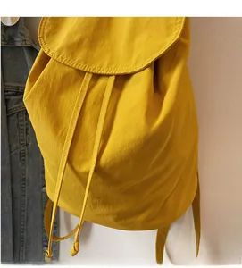 Detail of soft yellow fabric texture and drawstring closure on minimalist backpack