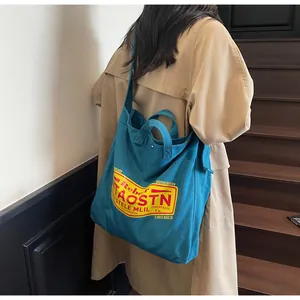 Detail of a large navy canvas tote bag with a retro logo shown on a person's shoulder