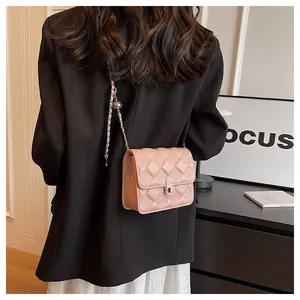 Detail of pink quilted crossbody bag with silver twist lock and chain on black blazer