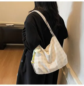 Détail du sac à bandoulière en toile à damier avec breloque peluche et patch cuir