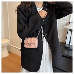 Detail of light pink quilted mini bag with metal chain strap on female model jacket