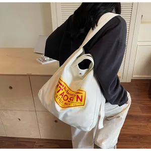 Detailed view of white canvas tote bag with red and yellow vintage lettering print