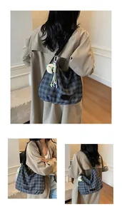 Détail du sac à carreaux avec breloque lune en peluche et pompon sur trench-coat